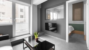 Un salon moderne avec une grande fenêtre, un téléviseur à écran plat et une plante en pot.