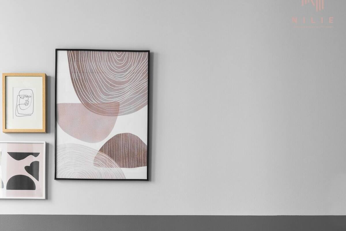 Un salon moderne avec un canapé en cuir noir, une petite table d’appoint ronde en bois sur laquelle est posée une plante en pot, et des œuvres d’art abstraites accrochées au mur.
