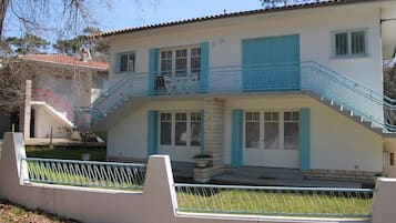 Un bâtiment à deux étages doté d’un balcon, d’un escalier et d’un petit jardin.