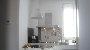 A modern kitchen with white appliances, a dining table set for four, and a window with curtains. - Elegant and modern flat, historical centre wi-fi M0270422272 (Venezia)