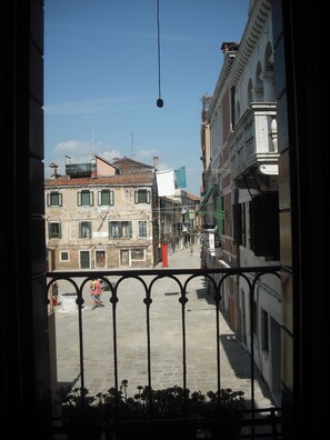 A balcony with a view of a narrow street lined with historic buildings, a clear sky, and a hanging light fixture. - Elegant and modern flat, historical centre wi-fi M0270422272 (Venezia)
