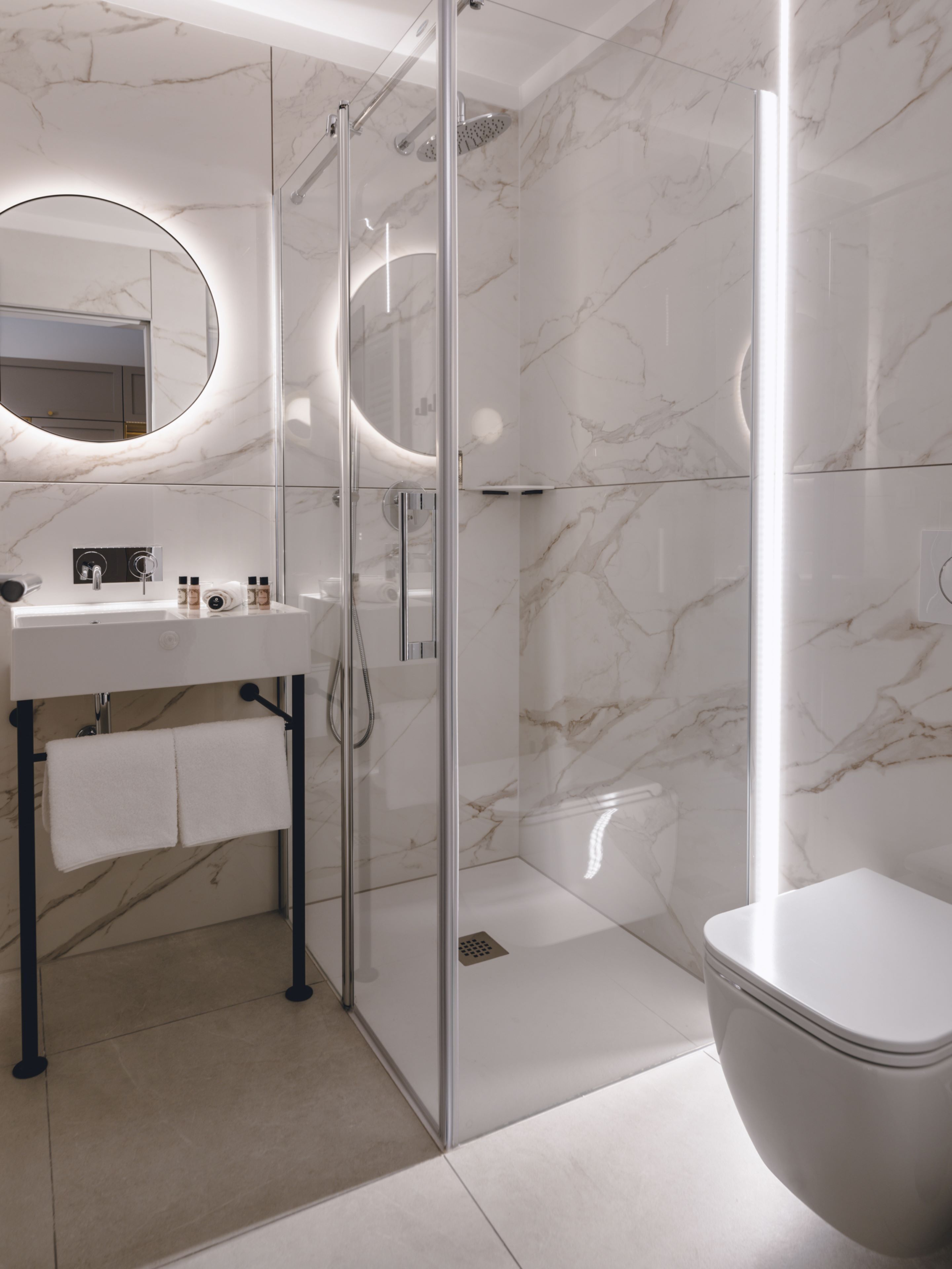Un baño moderno con ducha de vidrio, un lavabo blanco con espejo y un inodoro.
