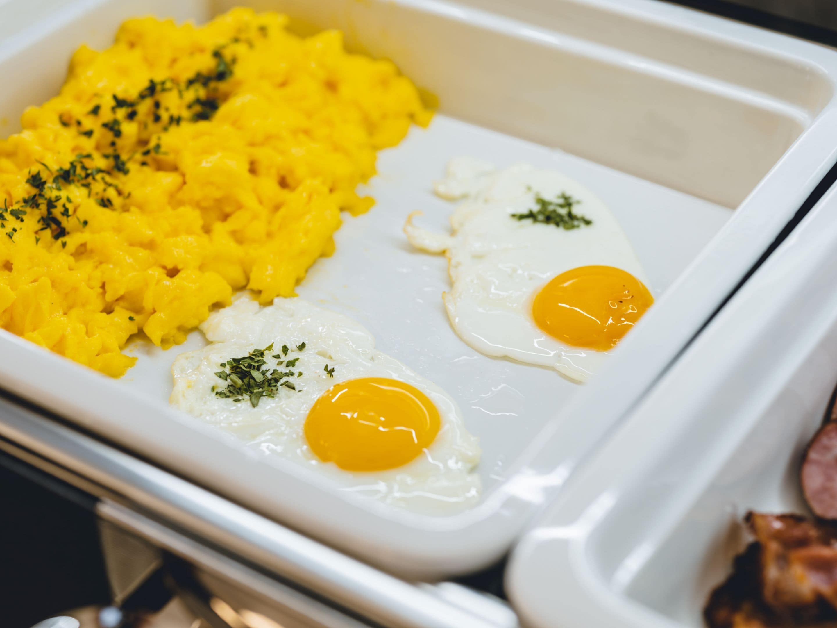A breakfast tray with scrambled eggs and hash browns.