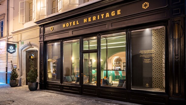 Et hotel med en klassisk facade, store vinduer og et skilt med teksten HOTEL HERITAGE.