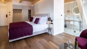 Et moderne hotelværelse med en stor seng, en glas brusekabine og et træloft.