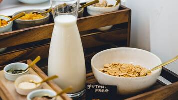 A breakfast tray with various food items, including a bowl of cereal, a glass of milk, and several small bowls with condiments.
