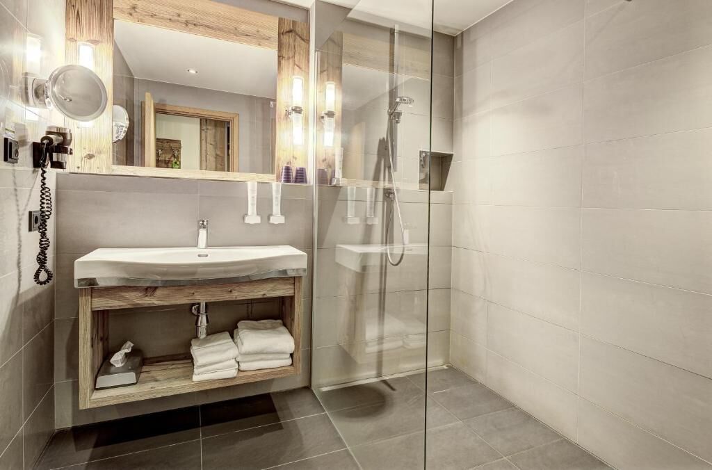 Une salle de bain moderne avec une douche à parois de verre, un meuble-lavabo en bois et un miroir au-dessus du meuble-lavabo.