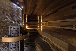 Una sauna con panche in legno e una parete in pietra.