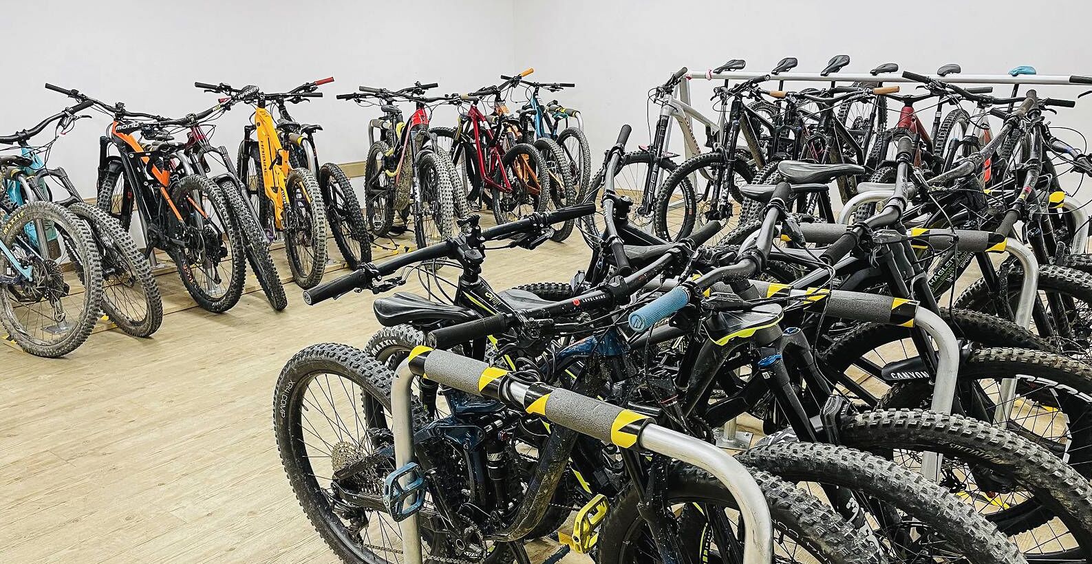 A room with multiple bicycles parked against the wall, indicating a possible rental service.