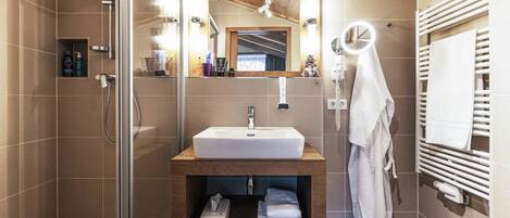 A modern bathroom with a glass shower enclosure, a wooden vanity with a sink, and a towel rack.