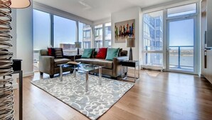 Un salón amplio con un conjunto de sofás, una mesa de centro y un gran ventanal con vistas a la ciudad.