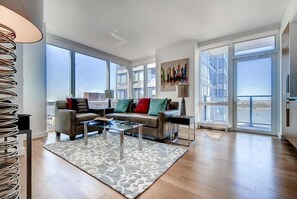 Relax in this stylish living room with a sofa set, coffee table, and patterned rug, offering a view of the surrounding buildings.