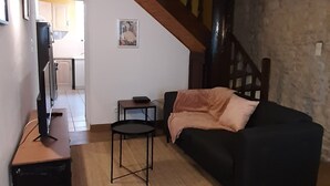A cozy attic room with a black sofa, a small table, and a wooden staircase.