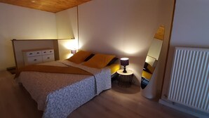 A bedroom with a bed, bedside tables, lamps, and a radiator.