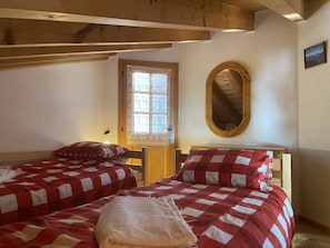 A room with two beds, each with a red and white checkered bedspread, a wooden headboard, a small wooden table, and a mirror on the wall. - Chalet Apartment, close to Bus Stop, free WiFi, 2 bedrooms & Stunning Views (Ollon)