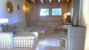 Una sala de estar acogedora con un conjunto de sofás, una mesita y un estufa de leña.