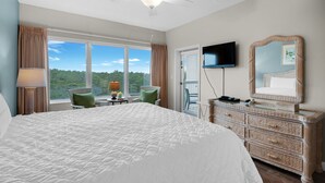 Ein Hotelzimmer mit einem großen Bett, einem Fernseher, einem Schminktisch und Blick ins Freie.