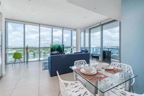 Enjoy expansive city and water views from the large window in this stylish living area, featuring a comfortable seating area and dining space.