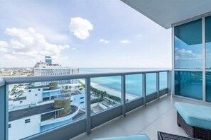 Enjoy the ocean view from this balcony with a wicker sofa and glass railing.