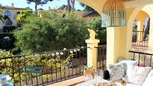 A balcony with a table set for dining, a chair, and a decorative bird statue. - Casa Alta Apartment, Moraira, with 2 large community pools (Moraira)
