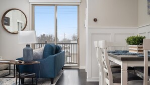 Un salon moderne avec un canapé bleu, un miroir rond et une table à manger avec des chaises.