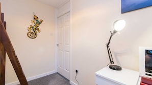 A room with a white desk, a desk lamp, a framed picture on the wall, and a wooden ladder. - Coventry- Jenner Pet Friendly 2 Bedroom Apartment (Coventry)