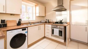 A modern kitchen with a built-in washing machine, oven, and stainless steel range hood. - Sublime Stays Parliament 2-bed Apartment (Derby)