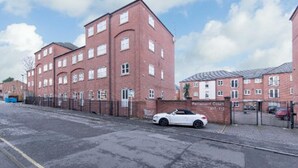 A red brick building with multiple windows and a gated entrance. - Sublime Stays Parliament 2-bed Apartment (Derby)