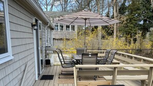 Eine Terrasse mit Gartenmöbeln, darunter Stühle und ein Tisch, sowie ein überdachter Grill.