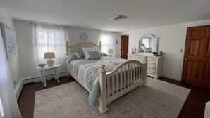 Ein Schlafzimmer mit einem hölzernen Bett, einem Nachttisch, einer Kommode und einem Spiegel.