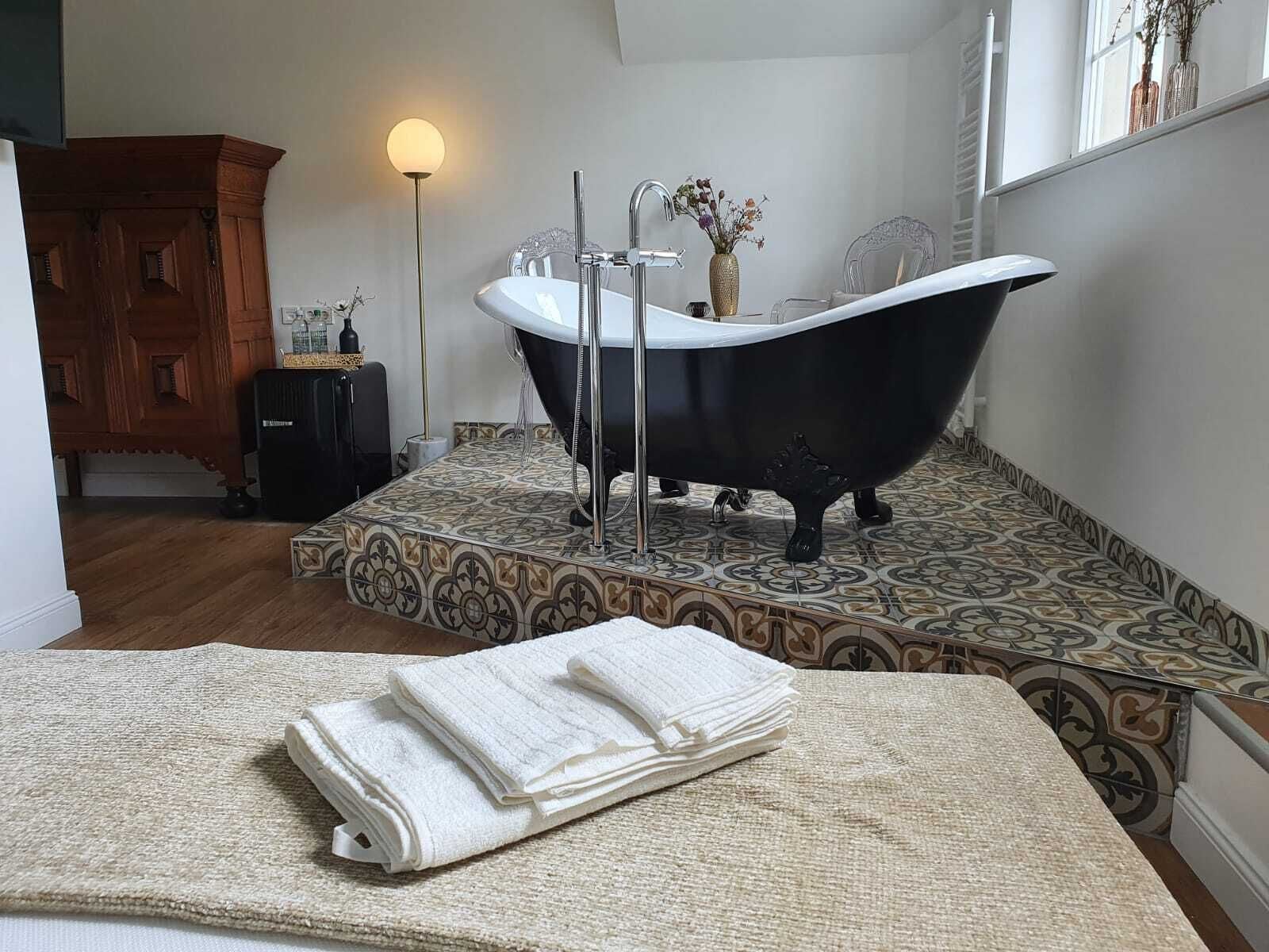 Ein Badezimmer mit freistehender Badewanne, einem Holzkabinent und einer Stehlampe.