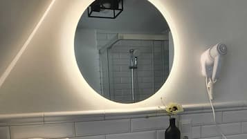 Un baño con lavamanos blanco, un espejo y un secador de pelo en la pared.