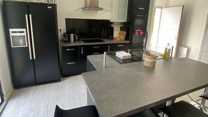 Et moderne køkken med sorte hårde hvidevarer, en central ø og barstole.