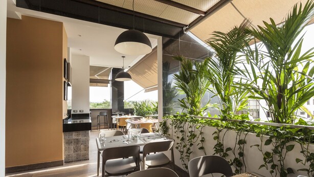 A modern dining area with a large table, chairs, and a view of the outdoors. - Hotel Park 85 (Cali)