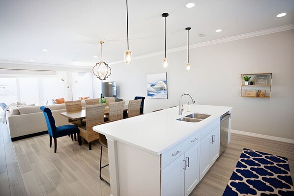 A modern kitchen with a central island, white cabinetry, and pendant lighting.