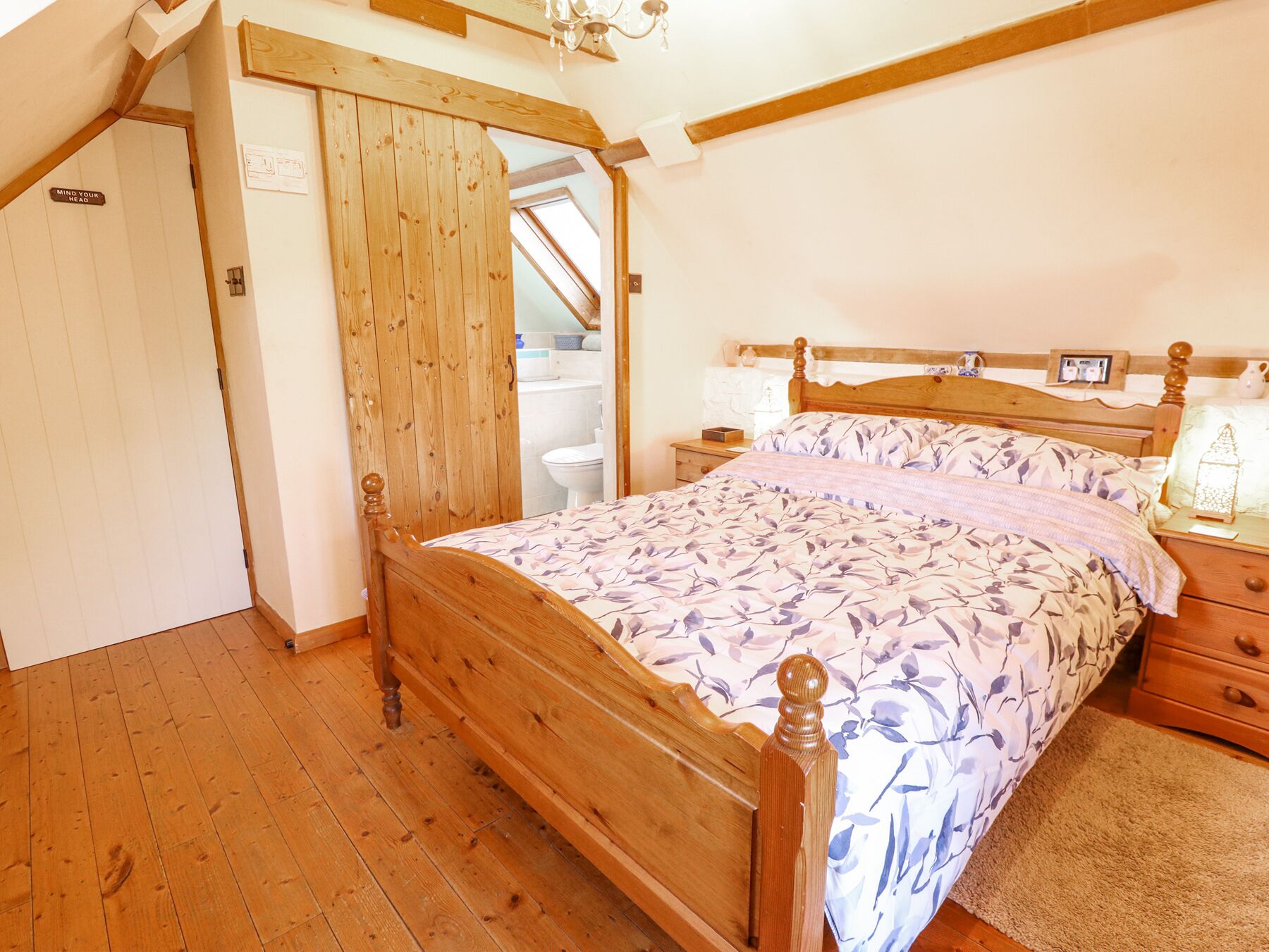 A bedroom with a wooden bed, a nightstand, a bedside table, and a wooden wardrobe.