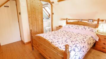 A bedroom with a wooden bed, a nightstand, a bedside table, and a wooden wardrobe.