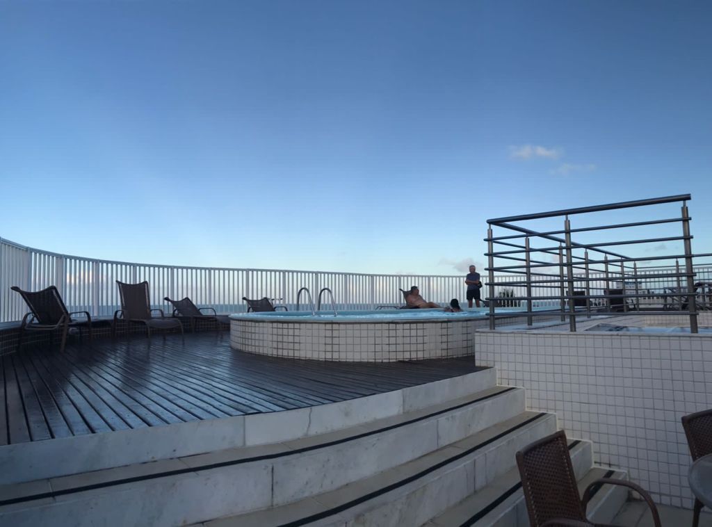 A rooftop deck with a pool, seating area, and a metal structure.