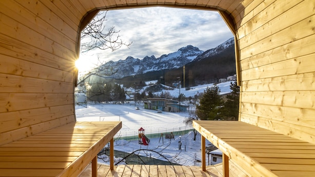 A wooden cabin with a balcony overlooking a snowy mountain landscape. - Hotel Garden (Andalo)