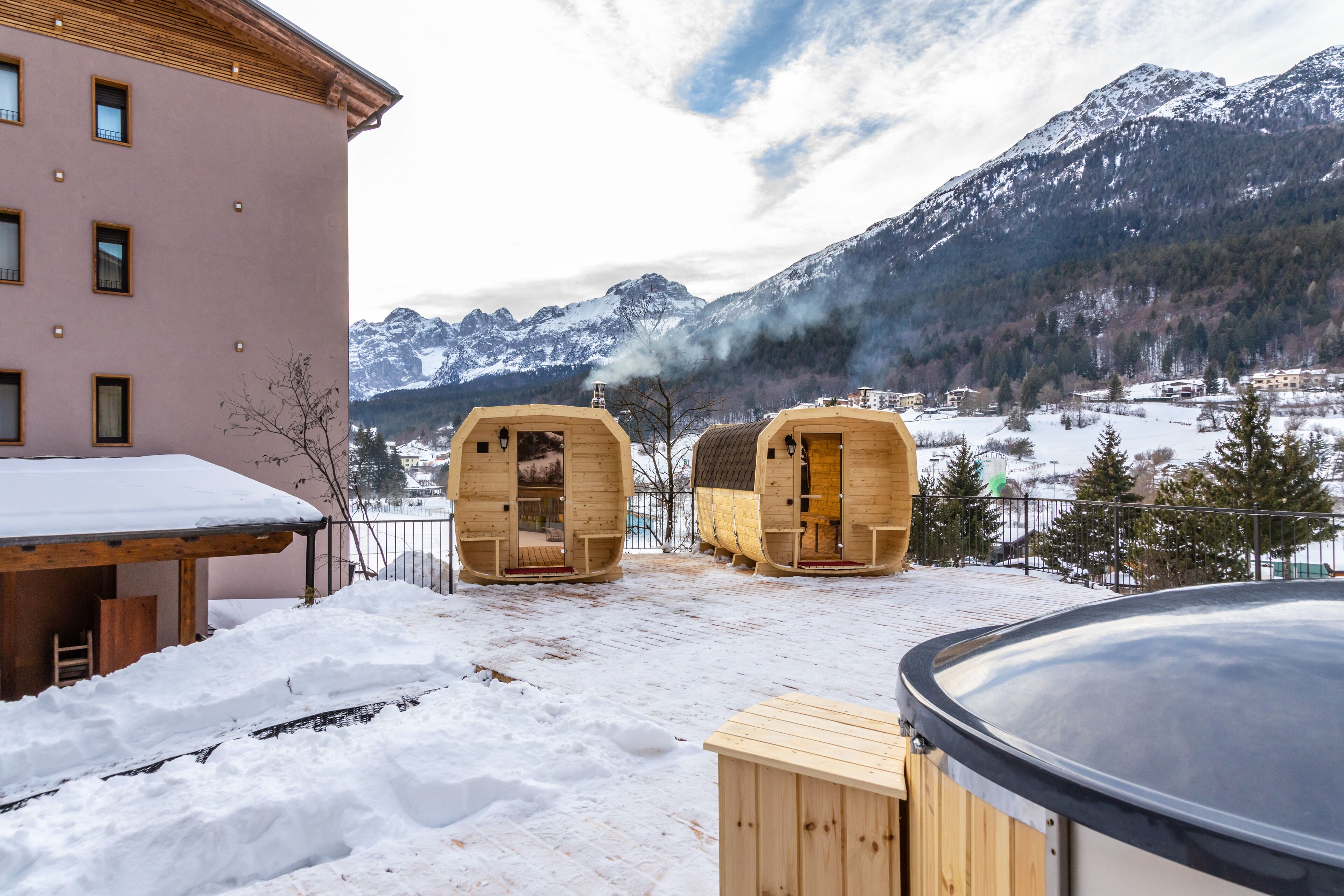 A wooden sauna structure with a view of snow-covered mountains.