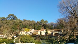 A hillside residential area with terraced houses, lush greenery, and a clear blue sky. - 2-room apartment Résidence Provençale Air-conditioned Parking Pool 2 km Sea (Villeneuve-Loubet)