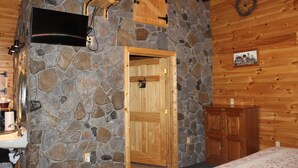 Une chambre rustique avec un mur en pierre, une porte en bois et un lit recouvert d’une courtepointe à motifs floraux.