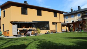 Een modern gebouw met twee verdiepingen, een plat dak, grote ramen en een overdekt terras.
