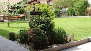 Een tuin met een welkomstbord, een hangmat en diverse planten.