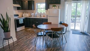 A kitchen with dark wooden cabinets, a white refrigerator, a microwave, and a dining table with four chairs. - Country Cottage Getaway (Waterloo)