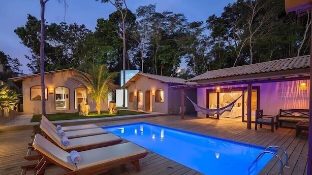 Ein Poolbereich mit Liegestühlen, einer Hängematte und einer Holzterrasse.