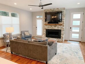 Cozy living room with a fireplace, sofa, armchair, and flat-screen TV.