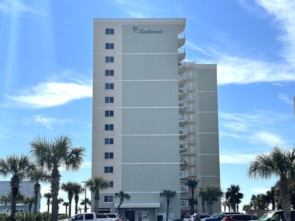Un hotel alto con un letrero que dice 'Tranquil', varios balcones y palmeras al frente.