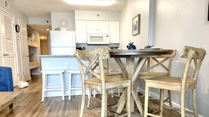 Une cuisine moderne avec des meubles blancs, un îlot central et des chaises en bois.