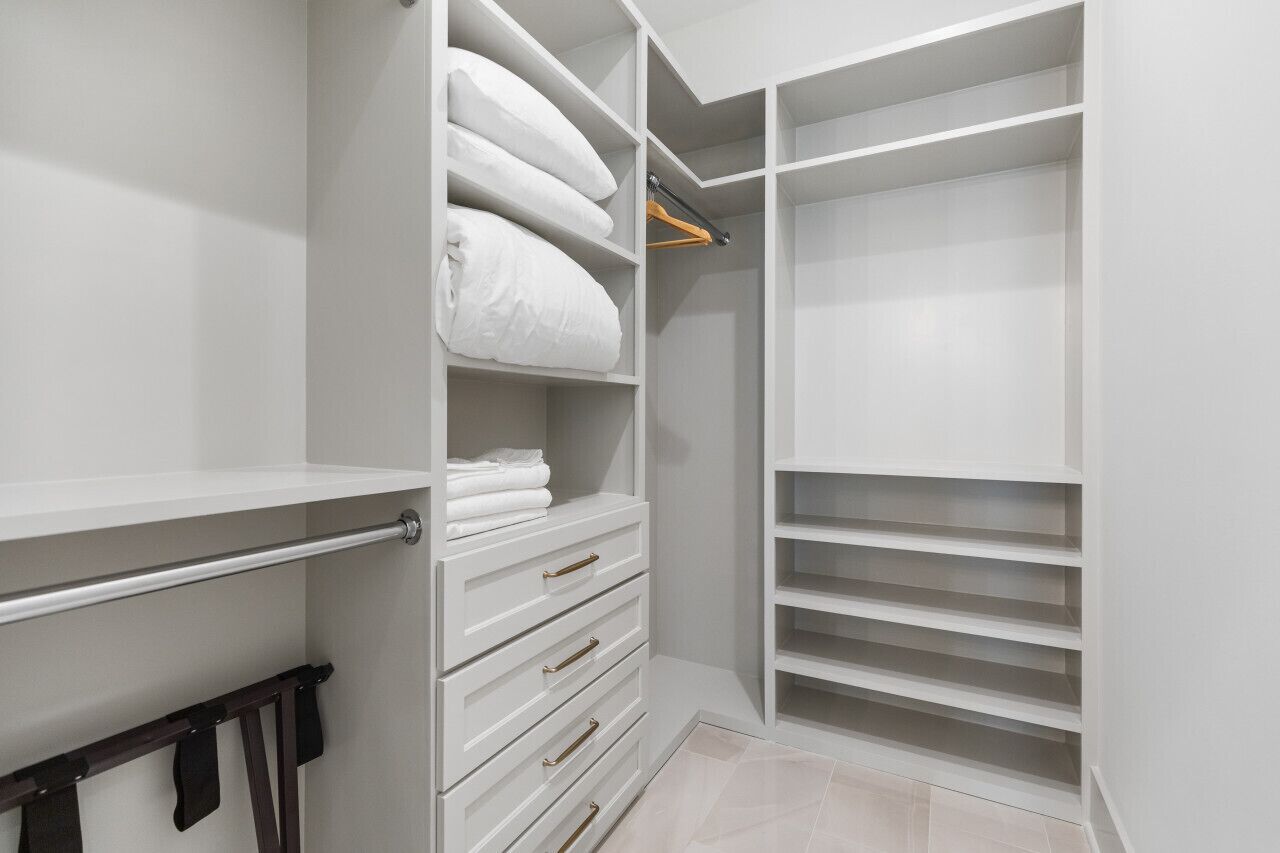 Un dressing avec des étagères, des tiroirs et une tringle à vêtements, le tout de couleur blanche.